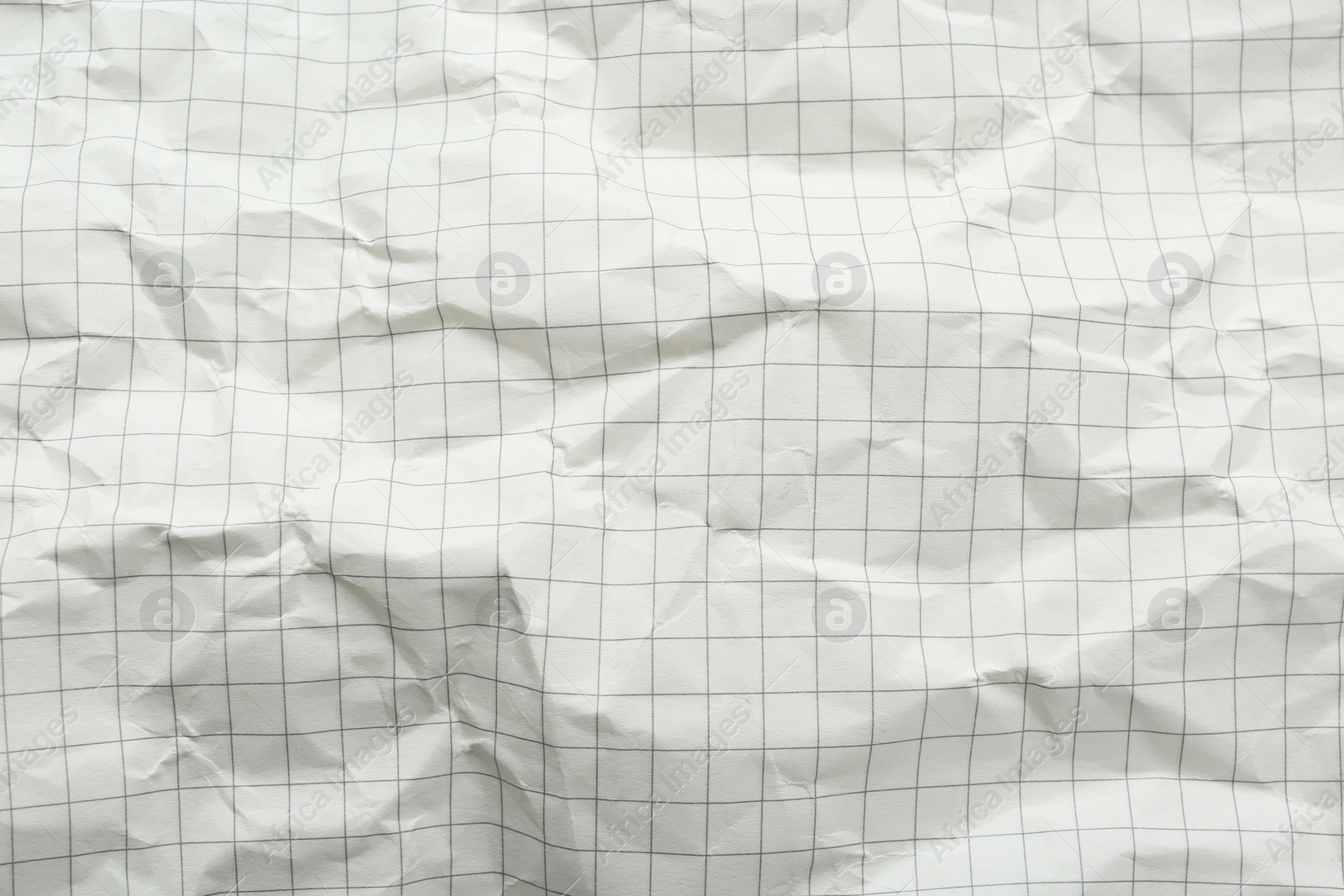 Photo of Crumpled checkered notebook sheet as background, top view