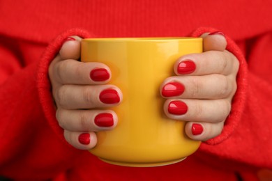 Woman with red polish on nails holding cup, closeup