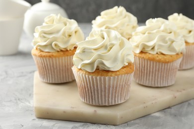 Photo of Tasty cupcakes with vanilla cream on grey table, closeup