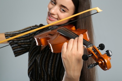 Photo of Beautiful woman playing violin on grey background, closeup