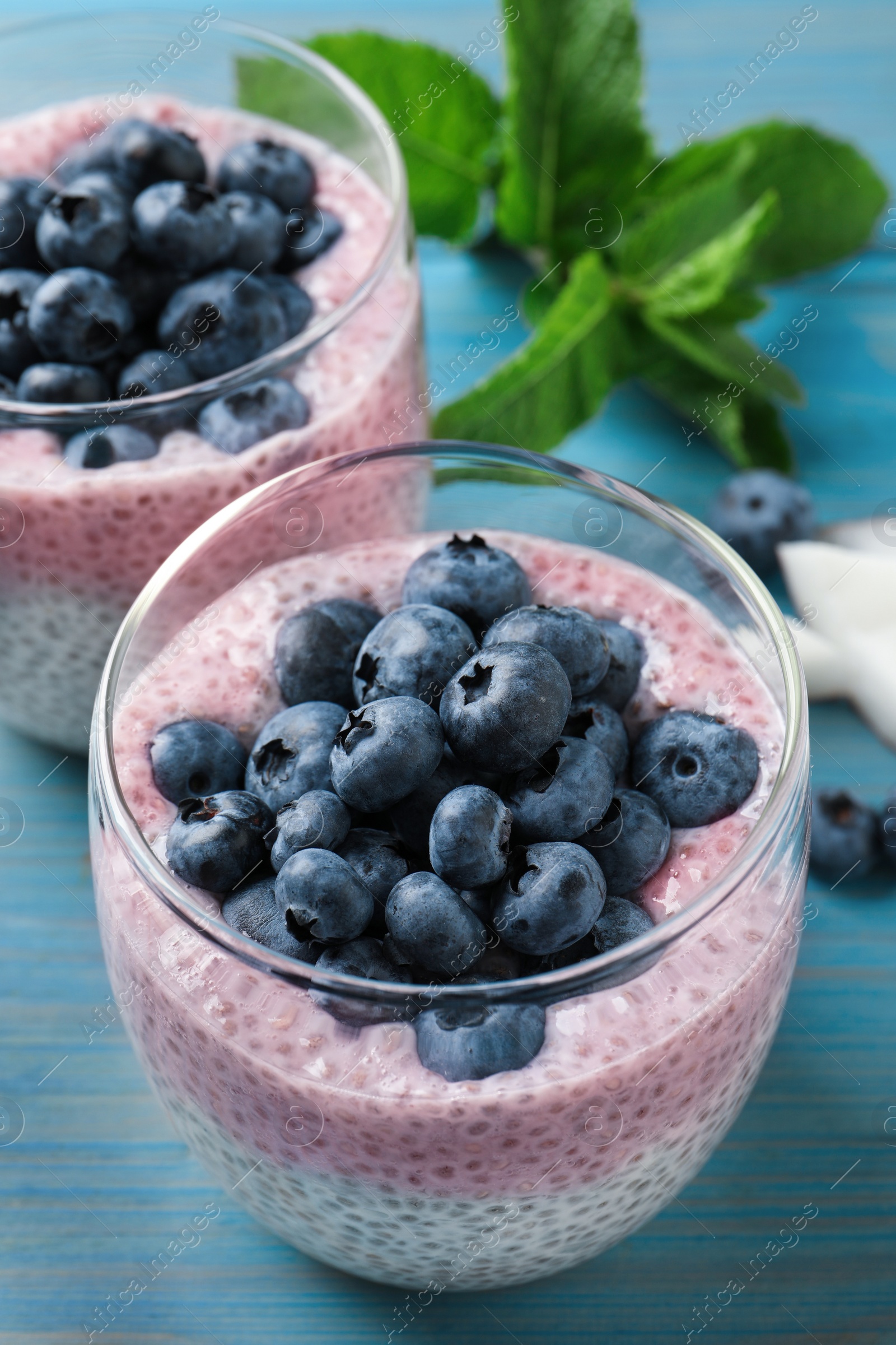 Photo of Delicious chia pudding with blueberries on light blue wooden table