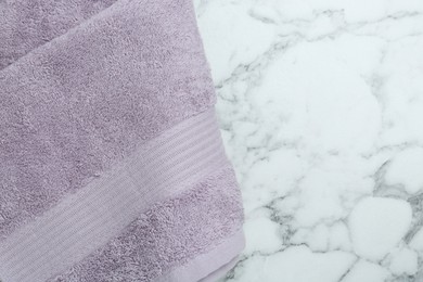 Violet terry towel on white marble table, top view. Space for text