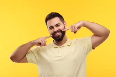 Photo of Man showing his clean teeth and smiling on yellow background