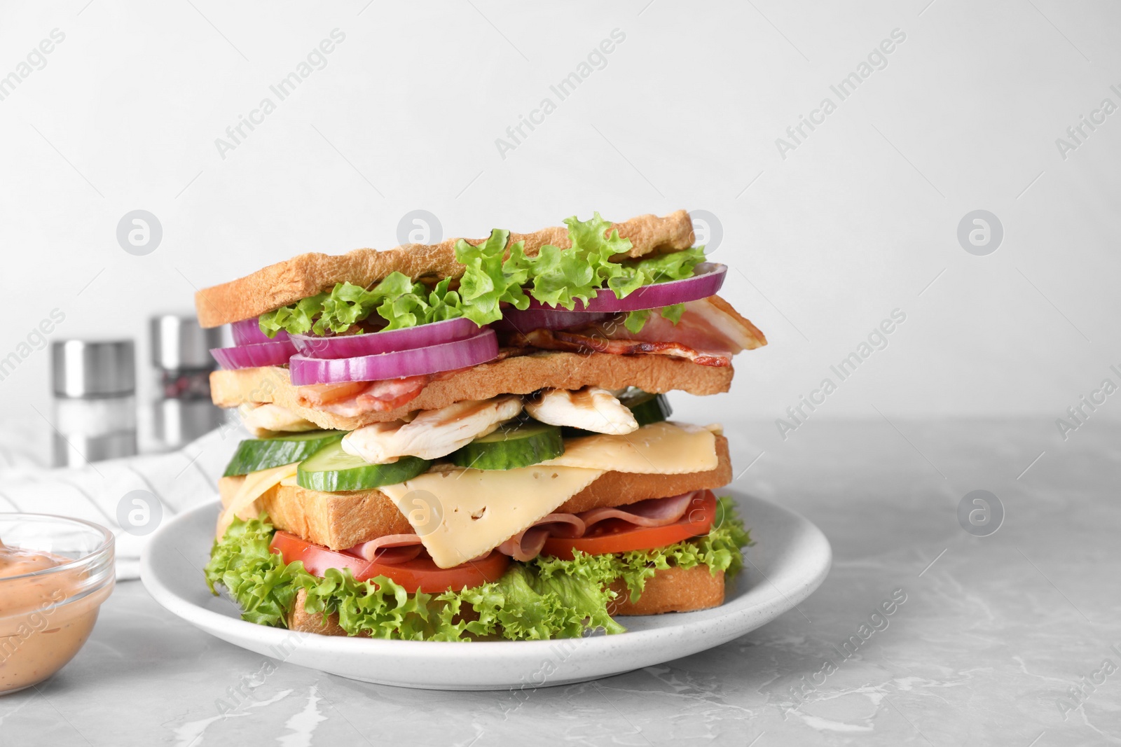 Photo of Tasty sandwich with chicken, ham and bacon on grey table