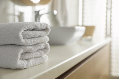 Photo of Stack of clean towels on countertop in bathroom. Space for text