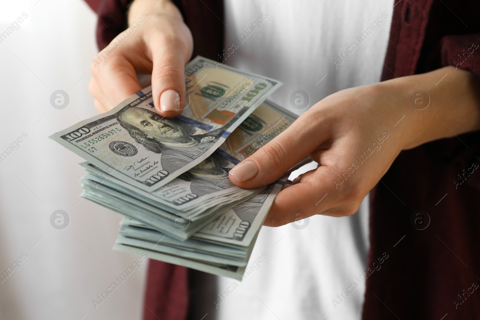 Photo of Money exchange. Woman counting dollar banknotes on blurred background, closeup