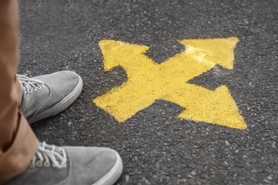 Photo of Man standing near arrow on asphalt, closeup