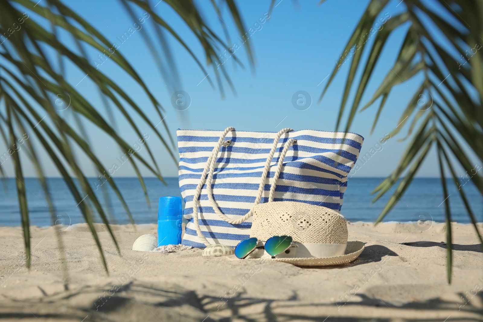 Photo of Stylish beach accessories on sandy sea shore