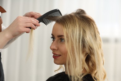 Hair styling. Professional hairdresser combing woman's hair in salon, closeup