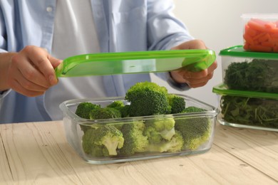 Photo of Man closing glass container with lid at wooden table, closeup. Food storage