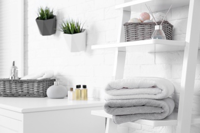 Stack of fresh towels on shelf in bathroom. Space for text