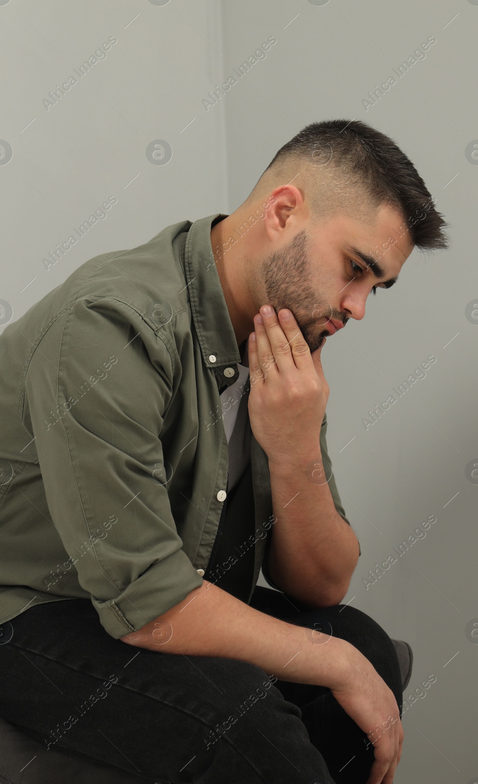 Photo of Sad man sitting near light grey wall