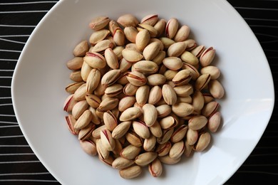 Many tasty pistachios on black table, top view