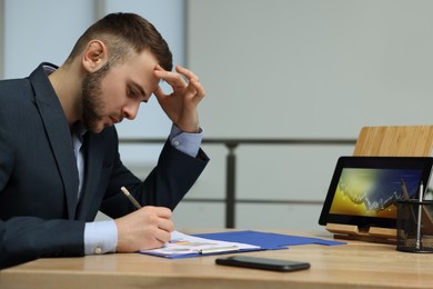 Photo of Forex trader working with tablet and documents at table in office