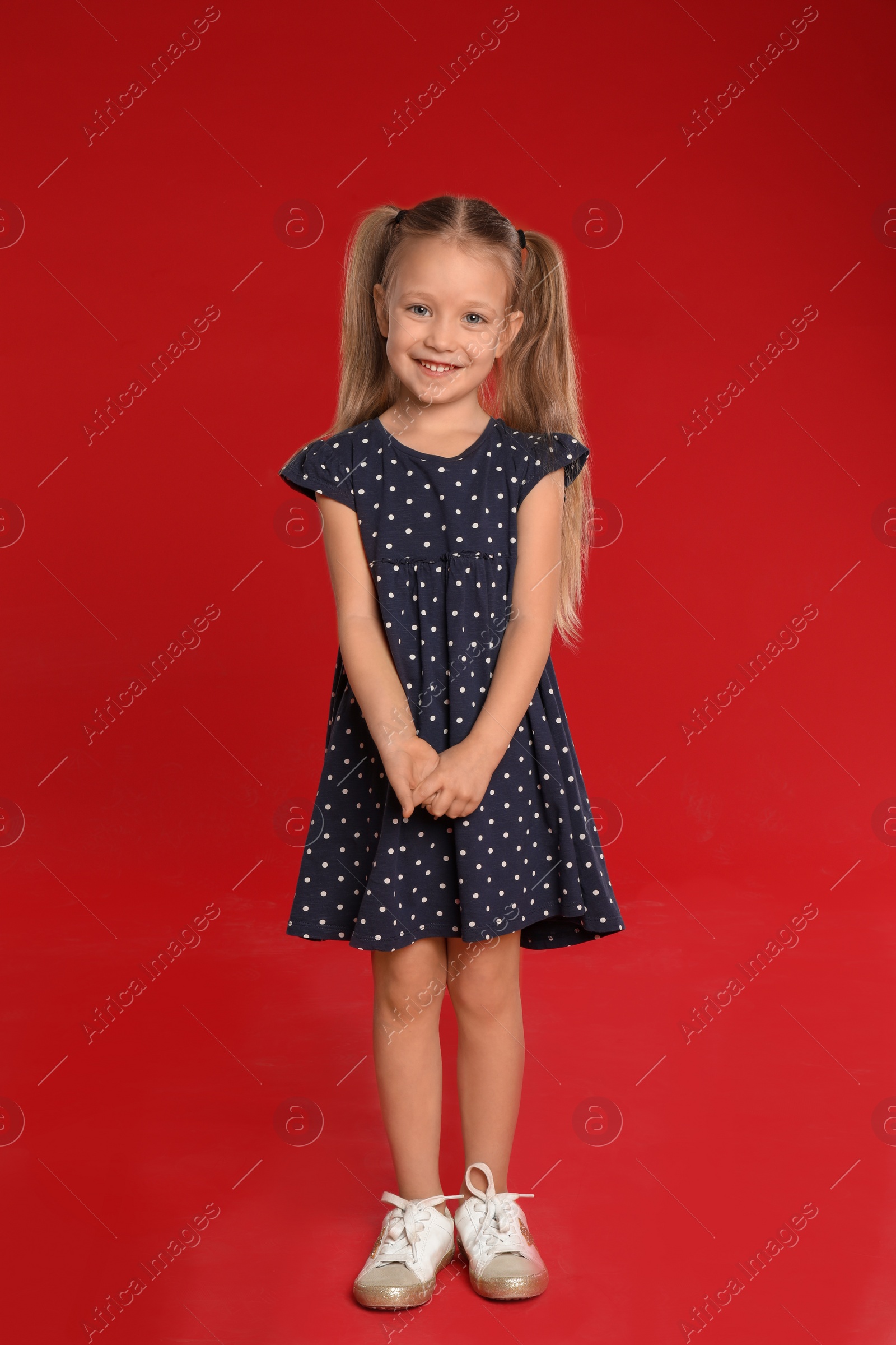 Photo of Portrait of cute little girl on red background