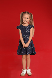 Portrait of cute little girl on red background