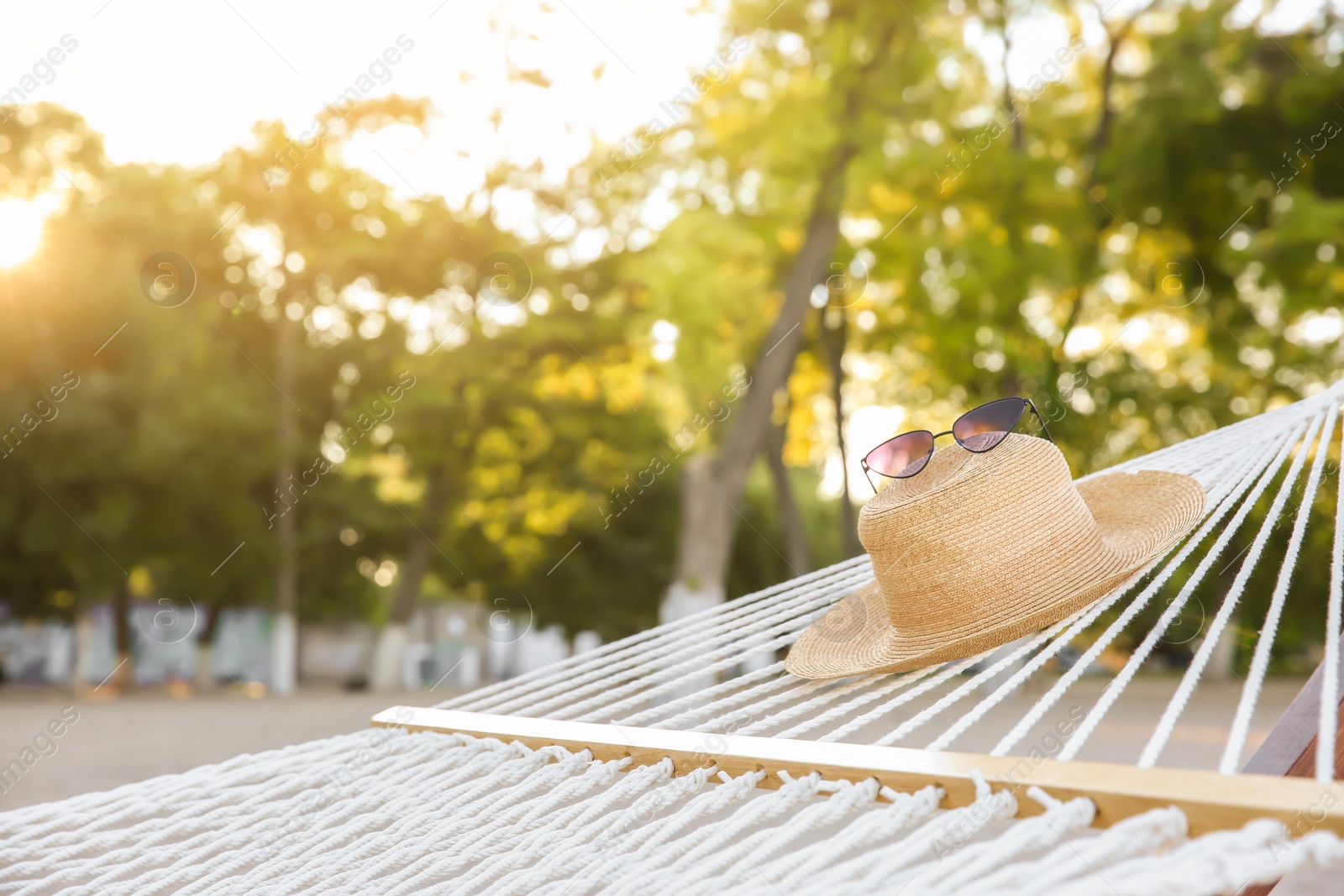 Photo of Comfortable hammock with straw hat and sunglasses at seaside