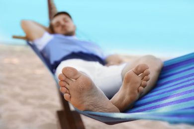 Photo of Young man lying in hammock at seaside. Summer vacation