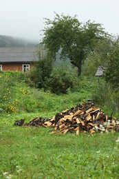 Photo of Pile of cut firewood on fresh green grass outdoors, space for text