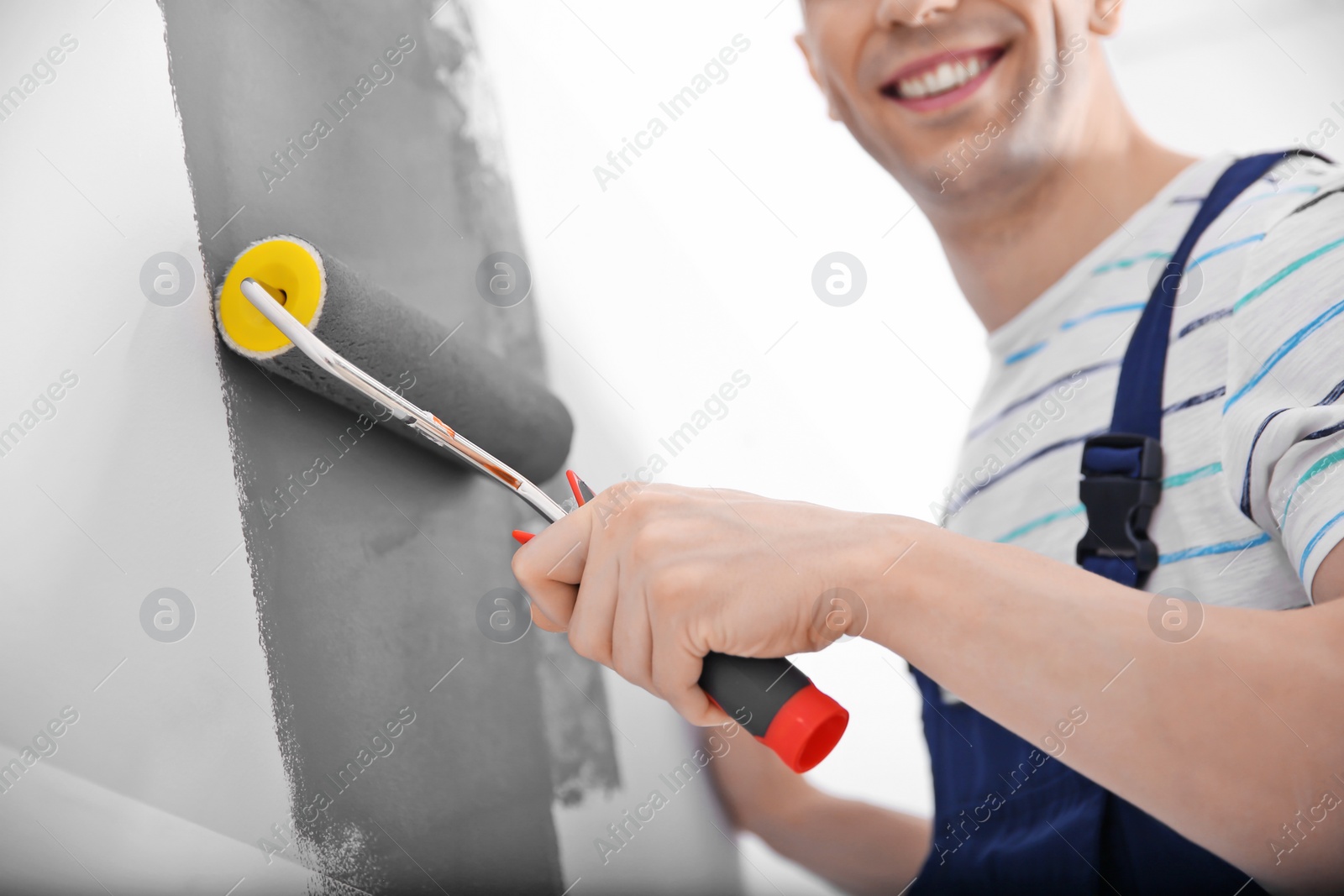 Photo of Young male decorator painting wall in room