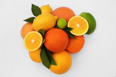 Photo of Different citrus fruits and leaves on white background, top view