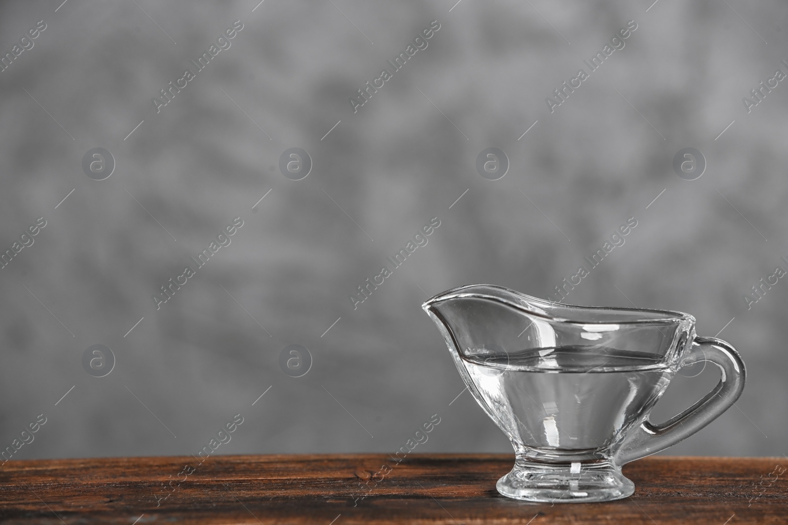 Photo of Gravy boat with vinegar on wooden table. Space for text