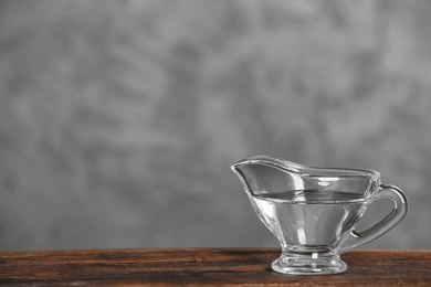 Photo of Gravy boat with vinegar on wooden table. Space for text