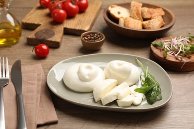 Photo of Delicious burrata cheese with arugula served on wooden table
