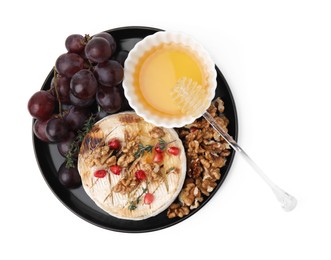 Photo of Plate with tasty baked camembert, honey, grapes, walnuts and pomegranate seeds isolated on white, top view