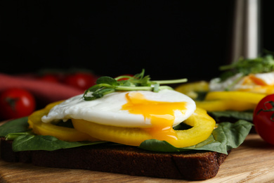 Delicious poached egg sandwich served on wooden board, closeup