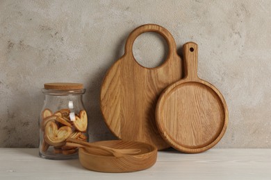 Photo of Wooden cutting boards, french palmier cookies, plate and spoons on white table near textured wall