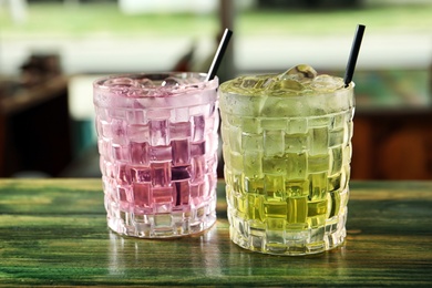 Photo of Glasses of delicious cocktails with ice on table