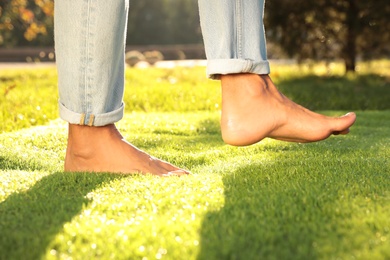 Man walking barefoot on fresh green grass, closeup