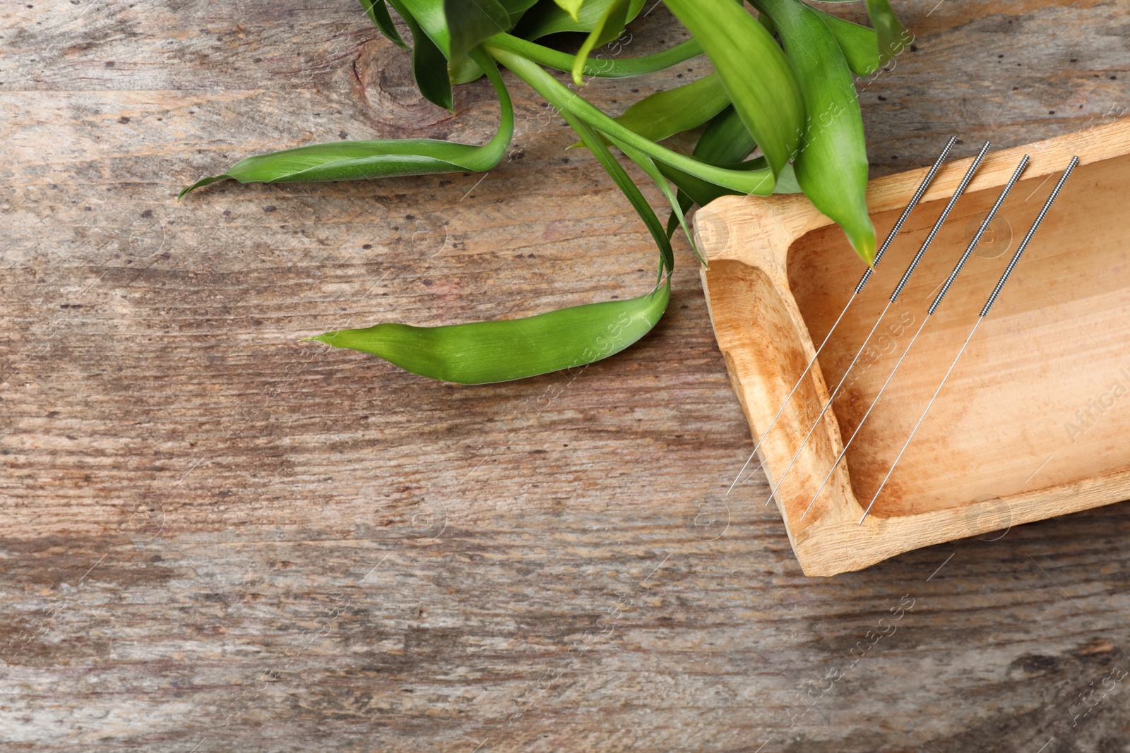 Photo of Flat lay composition with bamboo stick and acupuncture needles on wooden table