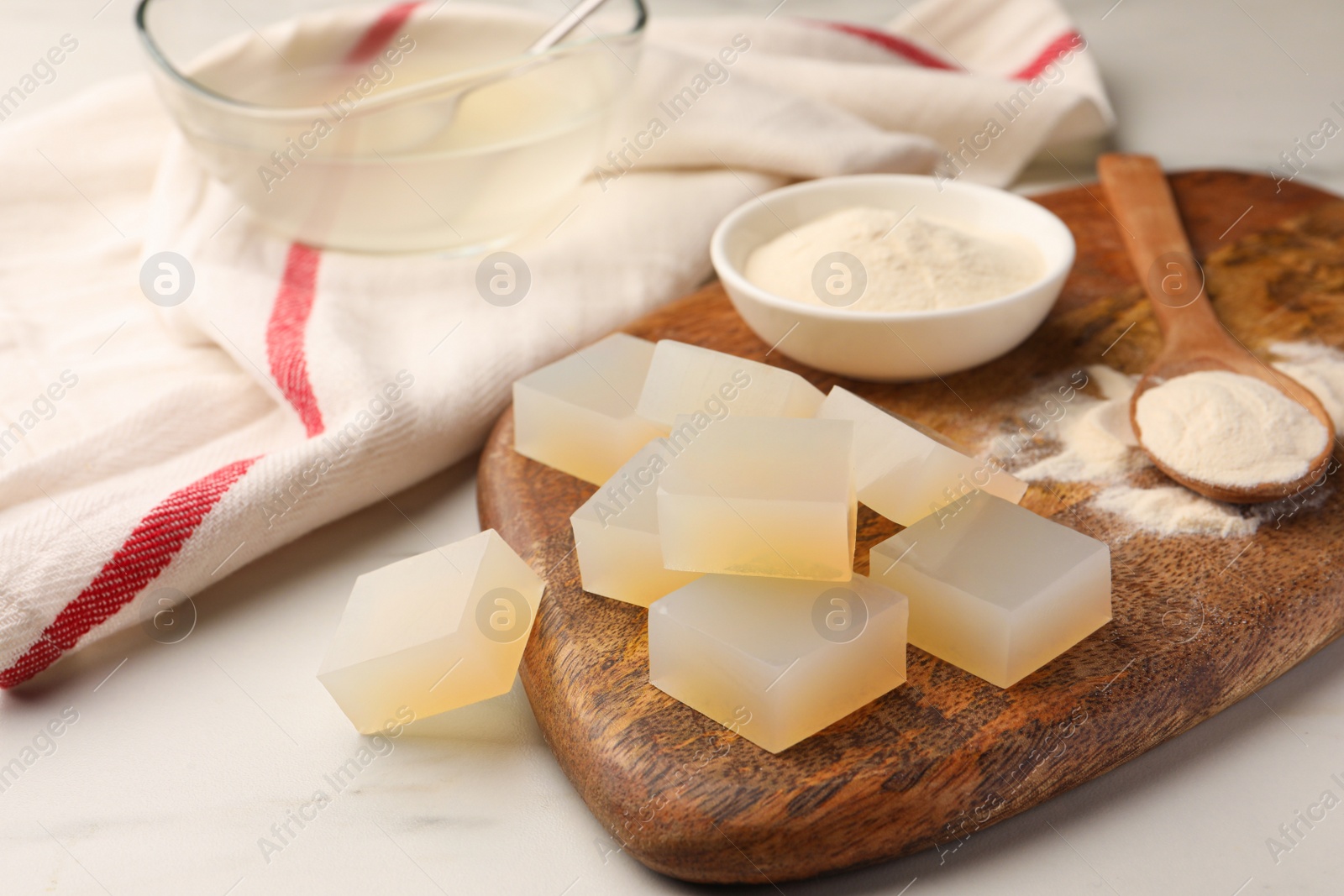 Photo of Agar-agar jelly cubes and powder on white marble table, closeup