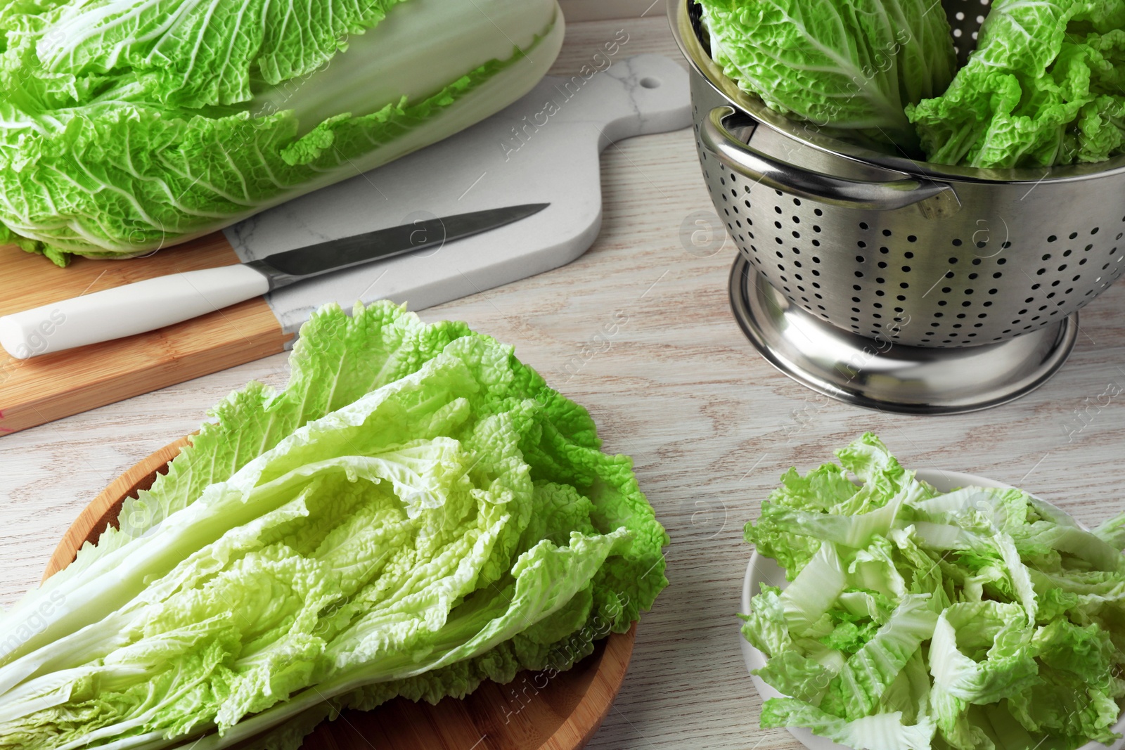 Photo of Whole and cut fresh ripe Chinese cabbages on white wooden table