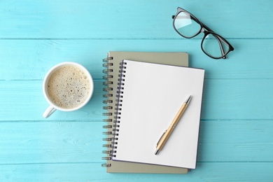 Photo of Flat lay composition with office stationery and cup of coffee on light blue wooden table