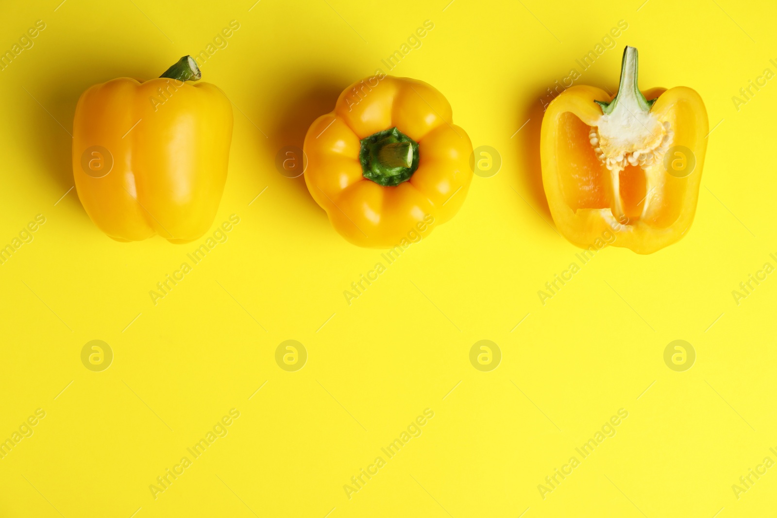 Photo of Ripe bell peppers on yellow background, flat lay. Space for text