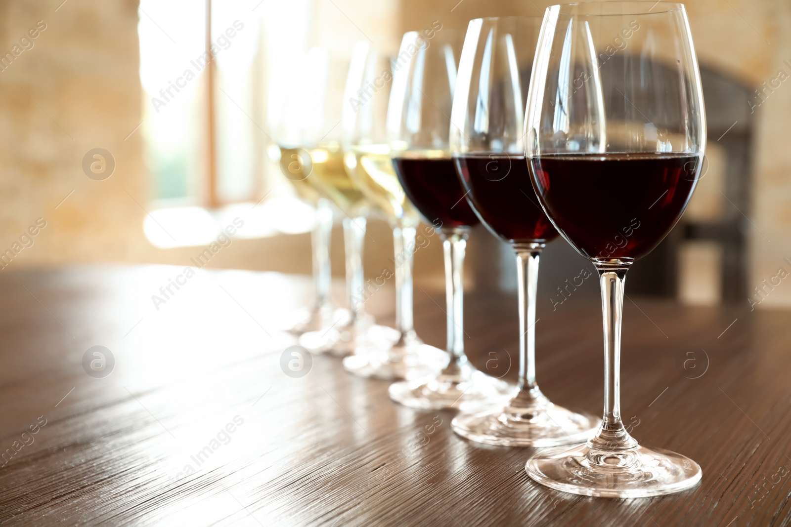 Photo of Glasses of white and red wines on wooden table