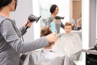 Professional female hairdresser working with little boy in salon