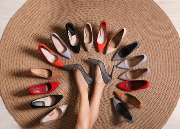 Photo of Young woman and different stylish shoes on wicker mat, top view