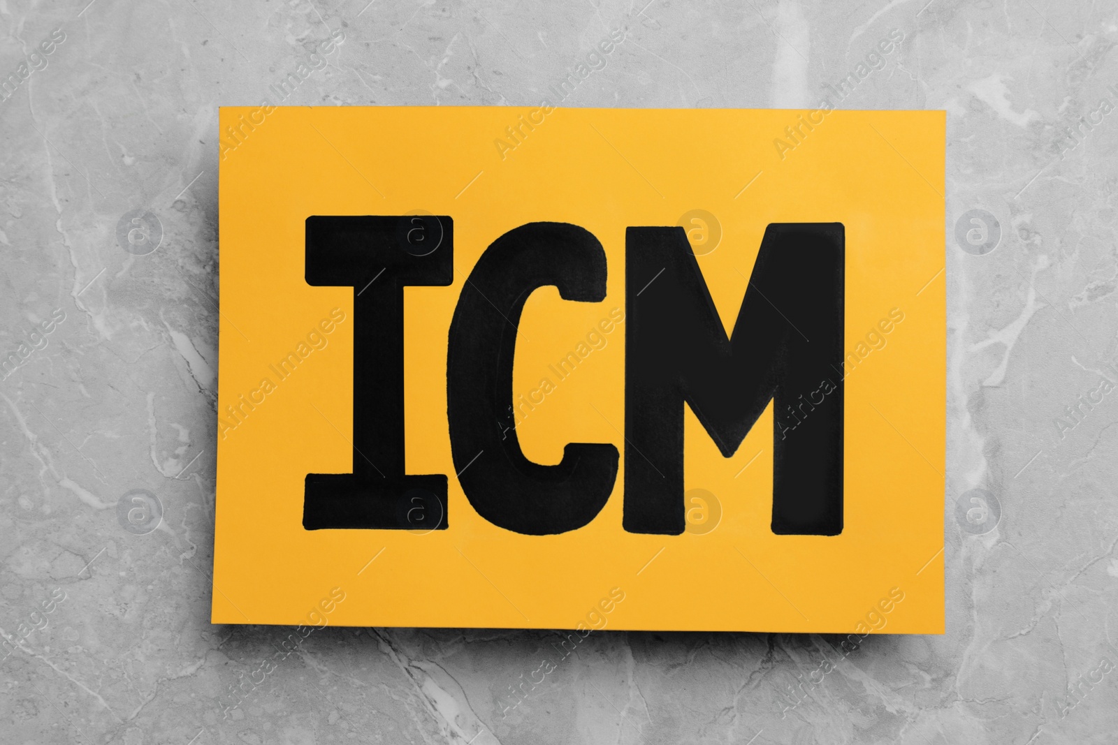 Photo of Orange paper with abbreviation ICM (International Cash Management) on light grey marble background, top view