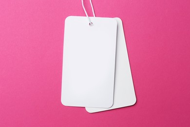 Tags with space for text on pink background, top view