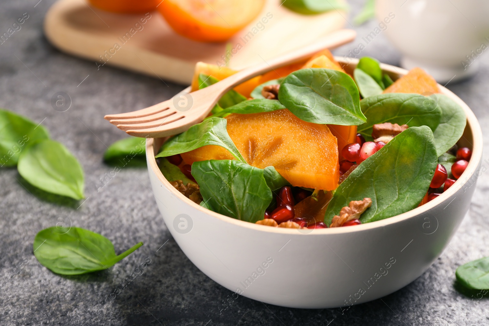 Photo of Delicious persimmon salad served on grey table, closeup