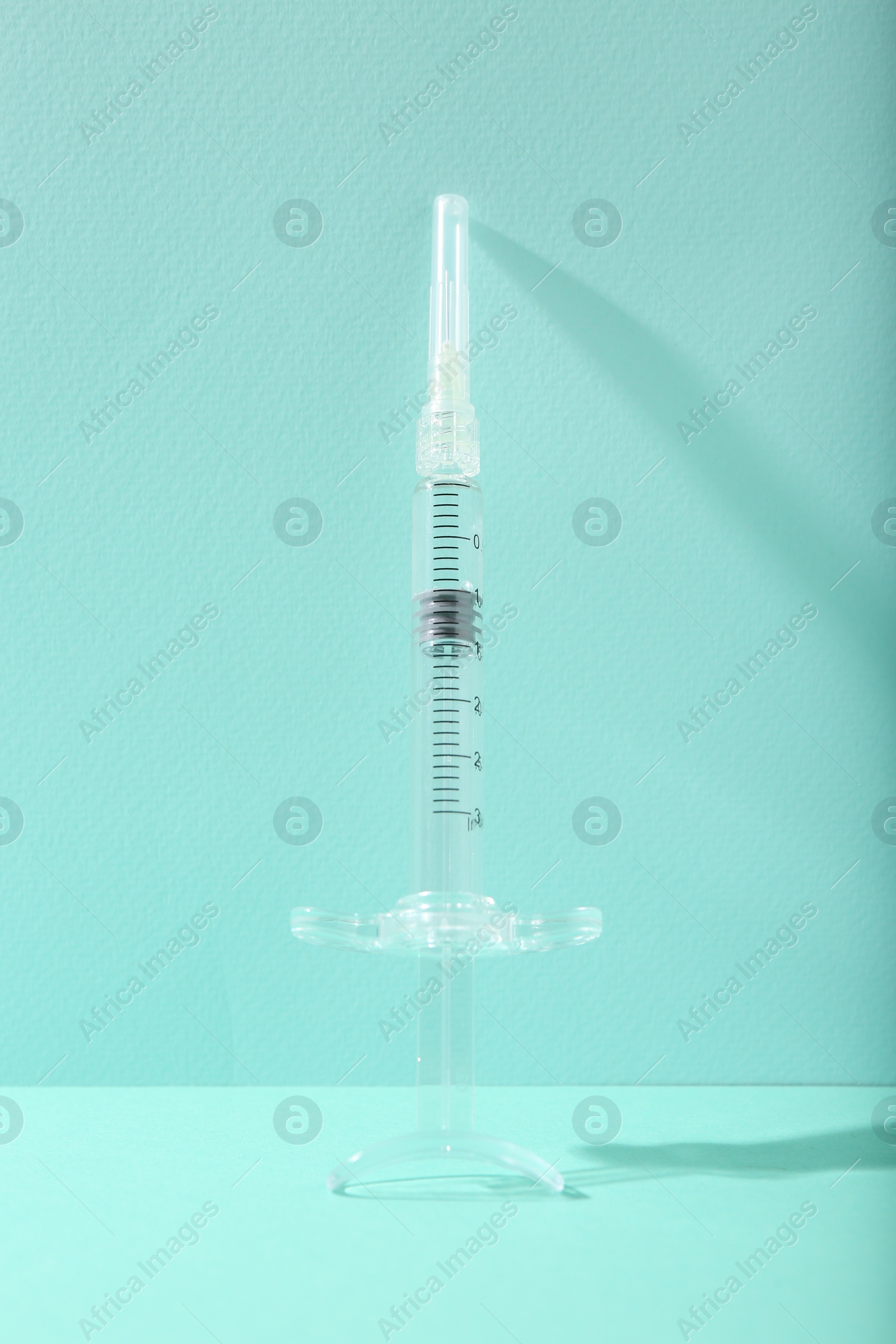 Photo of Cosmetology. One medical syringe on turquoise background