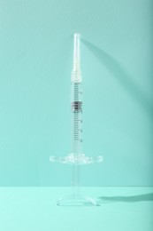 Photo of Cosmetology. One medical syringe on turquoise background