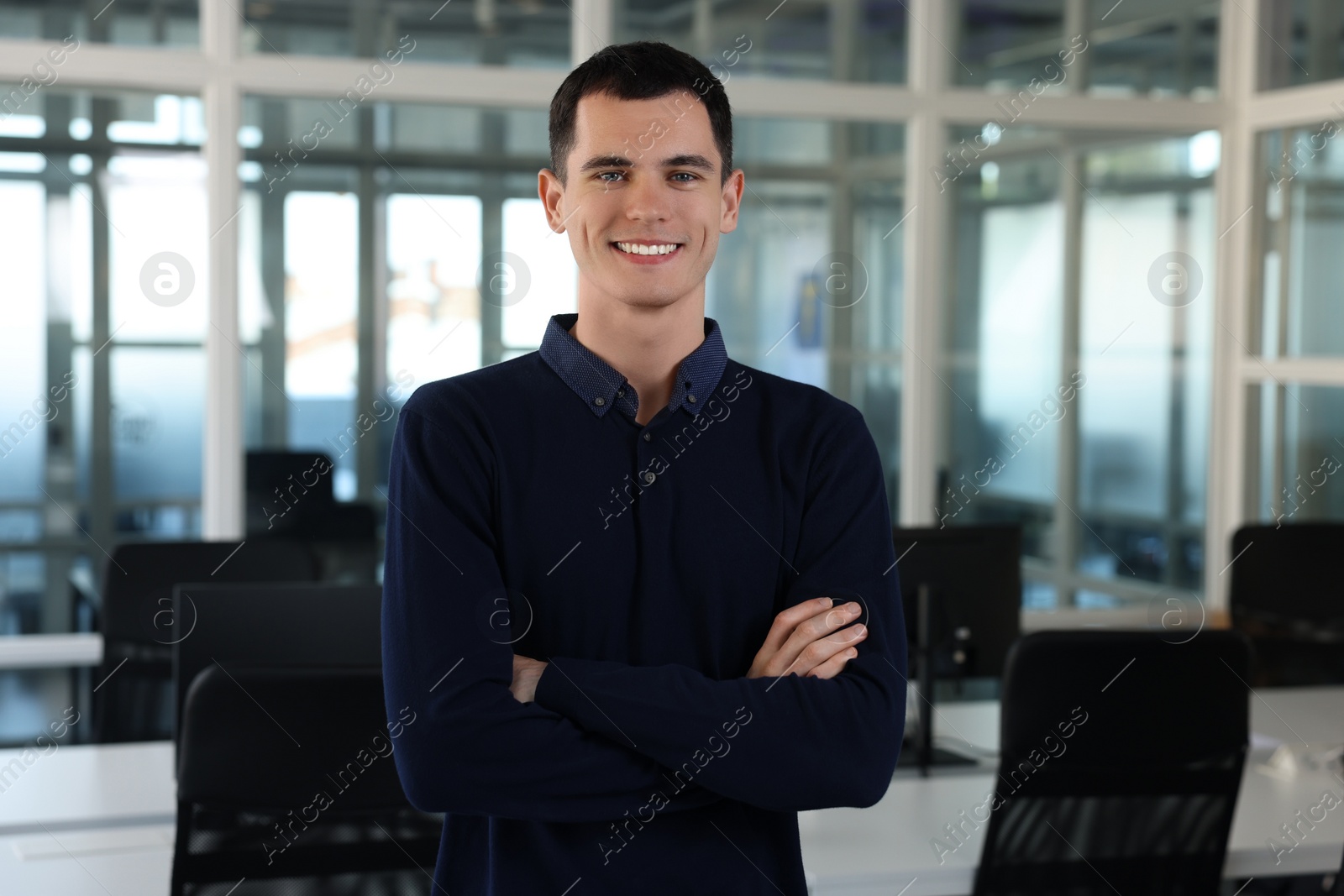 Photo of Handsome happy man with crossed arms in office