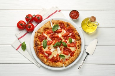 Delicious Margherita pizza, tomatoes, sauce, oil and server on white wooden table, top view