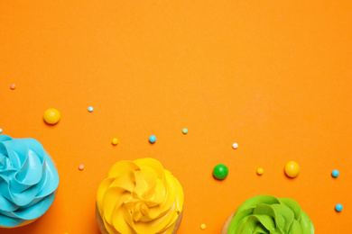 Colorful birthday cupcakes on orange background, flat lay. Space for text