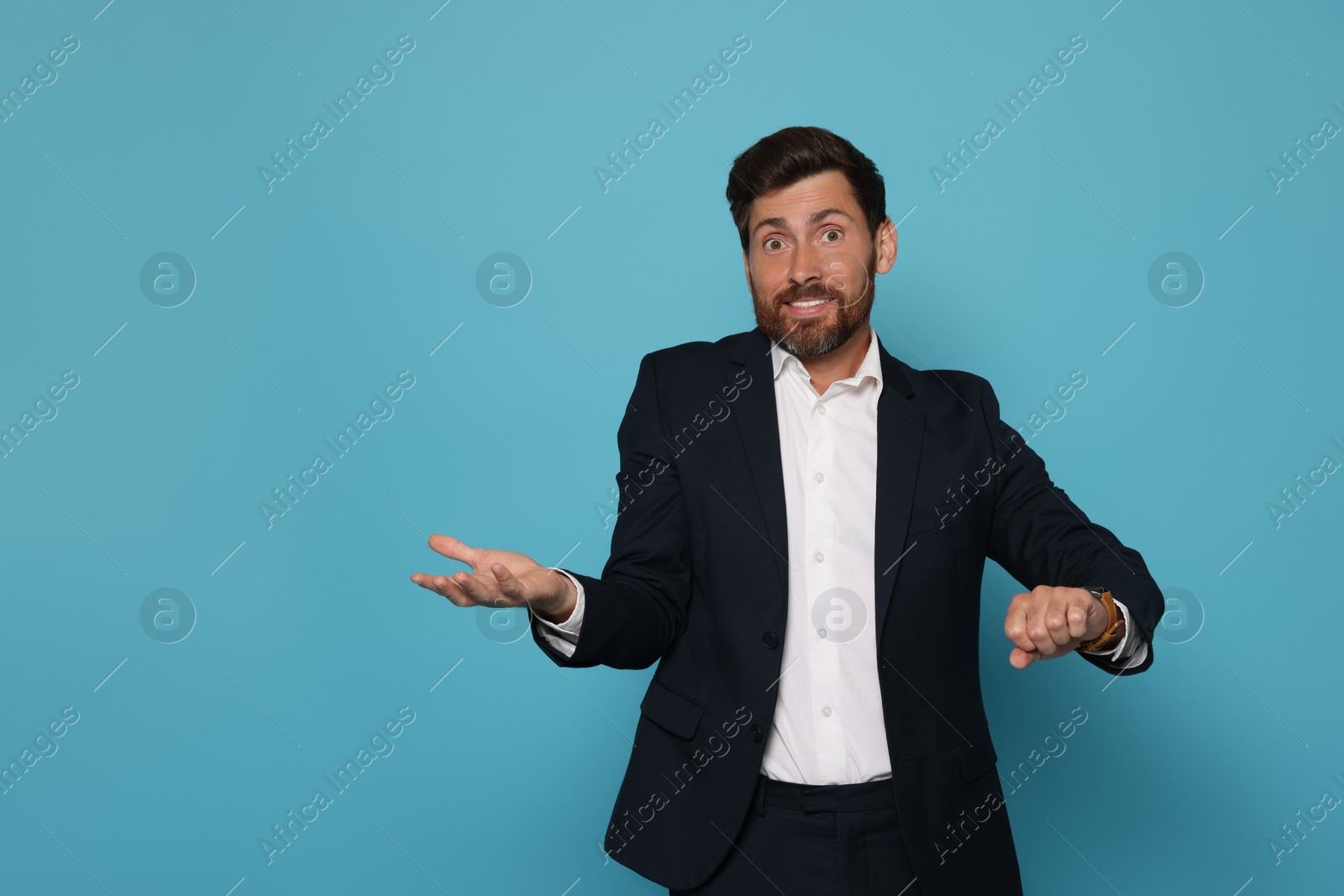 Photo of Emotional man checking time on light blue background. Being late concept